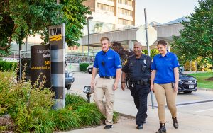 Three people walk down a sidewalk.