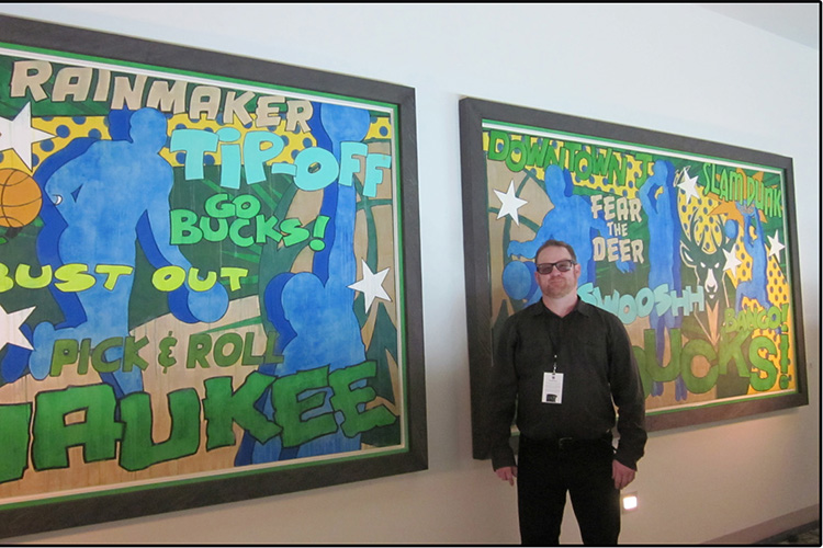 A man stands in front of two paintings.