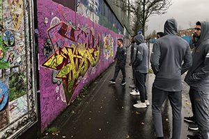 A group of players look at a wall painted with graffiti.
