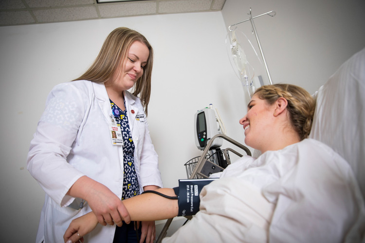 A female nurse takes the blood pressure of a person in a doctor's office