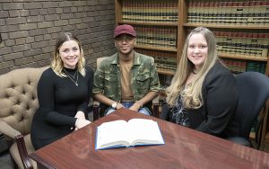 Three people sit at a table.