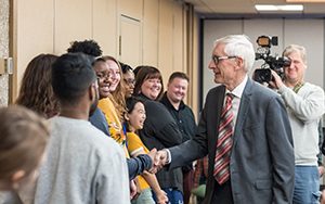 The governor shakes hands with students lined up along a wall.
