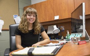 A woman sits at a desk.