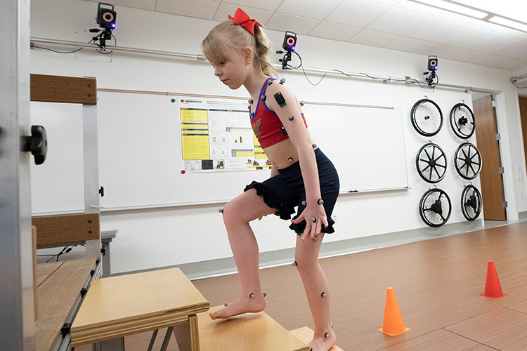 A young girl climbs steps at a mobility lab