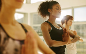 Three women stand in a yoga pose