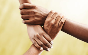 Photo of three hands, each holding another person's wrist