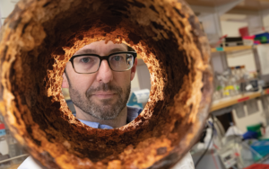 UWM professor Ryan Newton looks through sewer pipe segment.