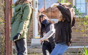 Three women dancing outside in a residential neighborhood