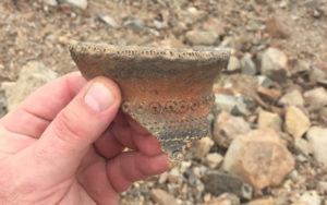 A pottery fragment held in someone's hand.