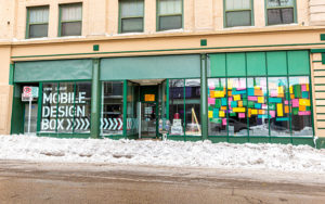 A storefront sits along a snow-plowed street.