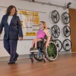 Mechanical engineering professor Brooke Slavens walks alongside a child wheelchair user.