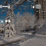 A path leads to Sandburg Residence Hall. Snow-covered trees line the path. Vintage rewind, closed caption and battery icons are on the image.