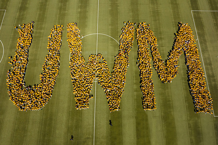 Aerial shot of hundreds of students arranged to form the letters UWM on the soccer field