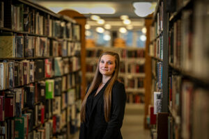 Naomi Kraut stands between two rows of books at a Milwaukee Public Library