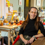 Pavonis Giron sitting in their studio and leaning against a table