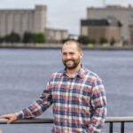 UWM alum Brennan Dow stands on a bridge overlooking the Milwaukee River.