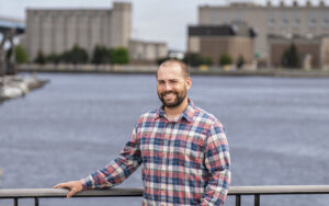 UWM alum Brennan Dow stands on a bridge overlooking the Milwaukee River.