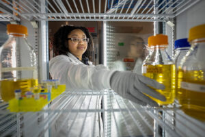 Freshwater sciences PhD student Kieyarrah Dennis reaches for a bottle of yellow liquid in the lab.