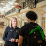 Barbara Meyer talks with an athlete in the gymnasium.