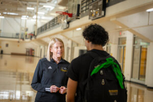Barbara Meyer talks with an athlete in the gymnasium.