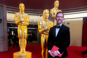 UWM alum Josh Rosenberg holds the winning envelope at the 2024 Academy Awards.