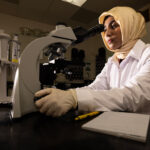 Biomedical sciences master's student Rashida looks into a microscope