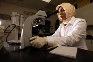 Biomedical sciences master's student Rashida looks into a microscope