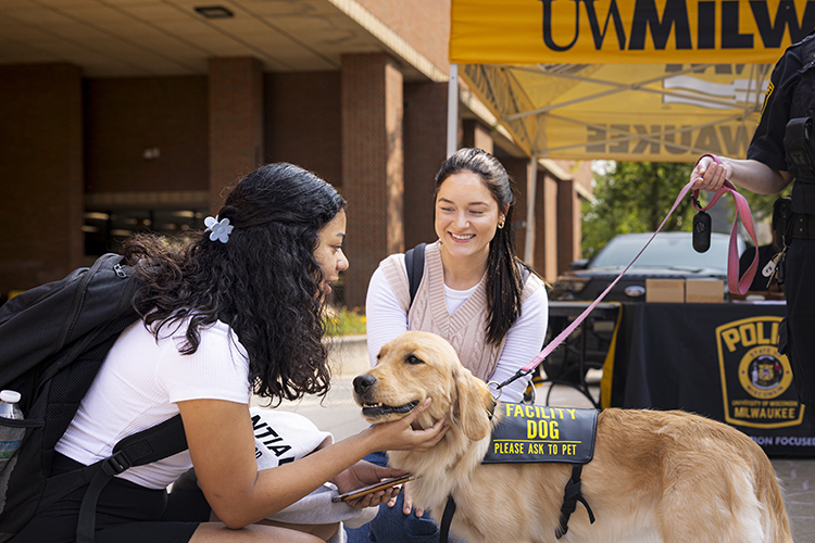 Ezmae, a campus comfort dog, gets some pets from two people on campus.