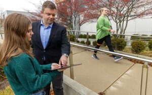 Assistant Professor of Biomedical Engineering Jacob Rammer discusses a mobility test with one student, as another walks by wearing monitoring equipment.
