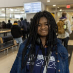 High school girl in a denim jacket and Class of 2029 shirt standing in a campus lobby.