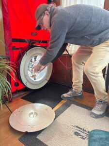 A man adjusts variable-speed fan mounted within a red adjustable tarp panel that is temporarily sealed into an exterior doorway to complete a diagnostic test.