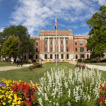 A view of the UW-Milwaukee campus, with flowers blooming in the foreground and a building in the background.