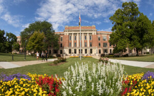 A view of the UW-Milwaukee campus, with flowers blooming in the foreground and a building in the background.