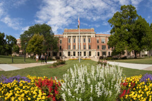 A view of the UW-Milwaukee campus, with flowers blooming in the foreground and a building in the background.