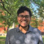 A man stands outside under some trees.