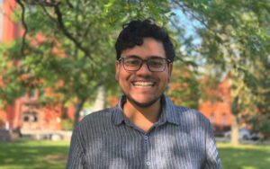 A man stands outside under some trees.