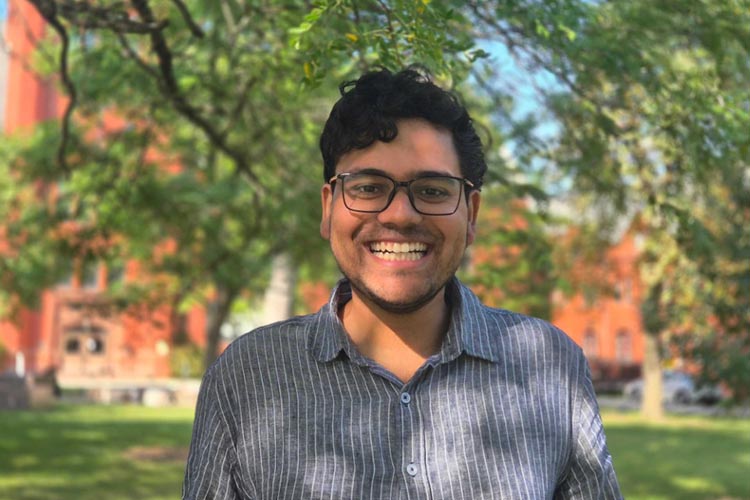 A man stands outside under some trees.