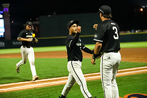 Two men in baseball uniforms give each other a fist bump.