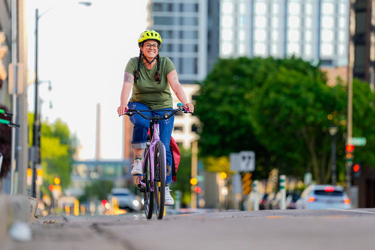 UWM public health alum Rachel Goochey rides her bike in a protected bike line in Milwaukee.