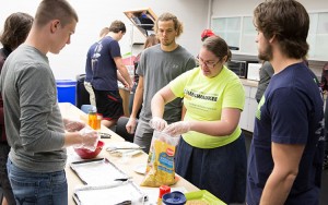 Senior Nutritional Sciences student Crystal Sciarini demonstrates the technique for making "Mock Fried Chicken," a lower-fat version of the popular favorite. Sciarini is one of several UWM students helping teach Junior Olympians how to create healthy meals to fuel their athletic performance. (UWM Photo/Troye Fox)
