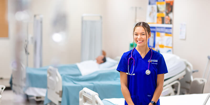 Female Nursing student in blue scrubs in sim center