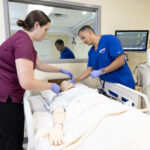image of two nursing students working on a manikin in the ICU simulation room
