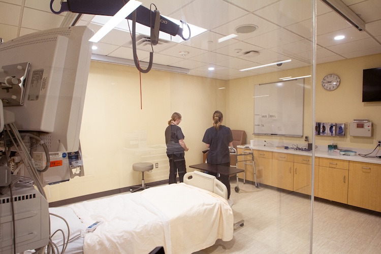two nursing students talk to a patient in the ICU simulation