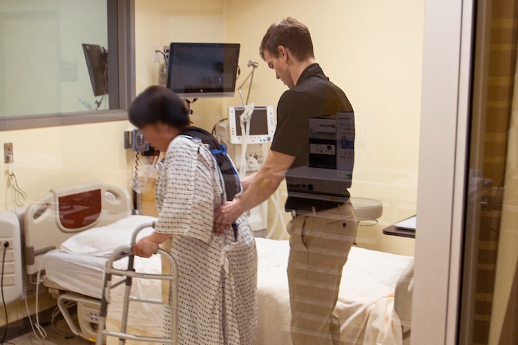 PT student helps the patient walk with a walker in the ICU simulation