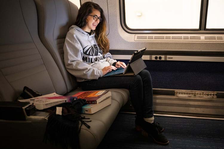 Online admissions student doing homework on a train