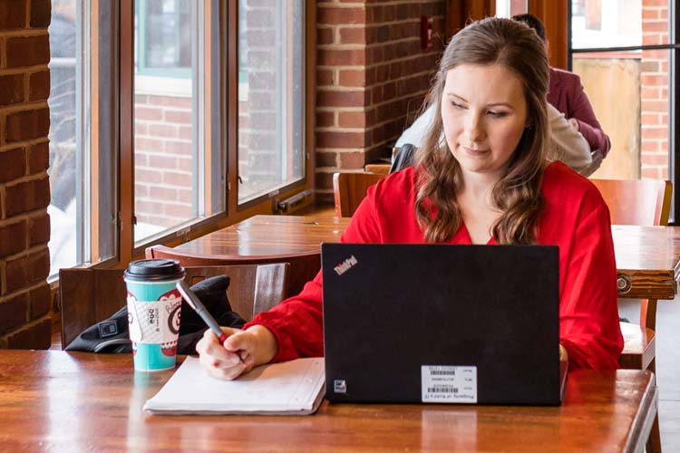 Online admissions student doing homework in coffee shop