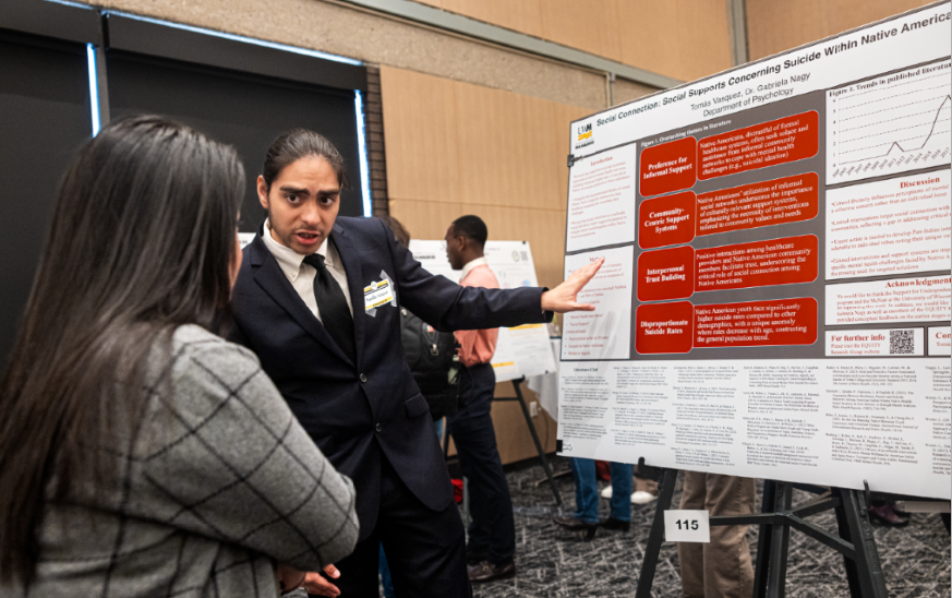 Student presenting research on a poster to an interested person