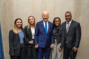 A group of four young people stands with President Joe Biden