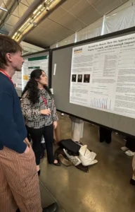 A young woman with long dark hair looks at her research poster showing images of U.S. Supreme Court Justices.
