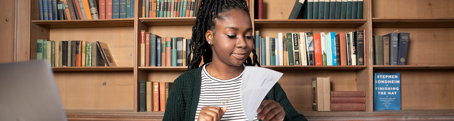 Middle school student reading in a room with books on shelves